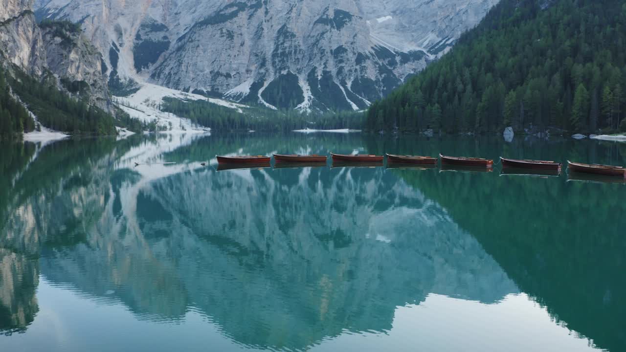 最美丽的布拉斯湖，也被称为Pragser Wildsee。白云石山脉,意大利。飞过碧绿平静的水面，小船在一片生涩。视频素材