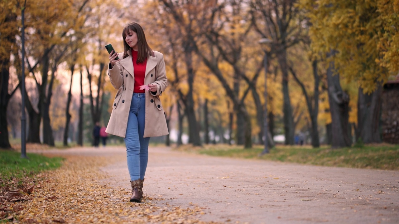 一个女人在公园里用她的智能手机视频素材