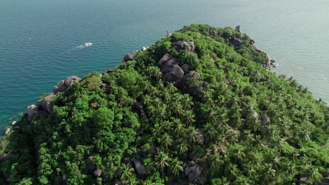 鸟瞰热带岛屿的海景，椰子树，岩石海岸线和一艘移动的船视频素材