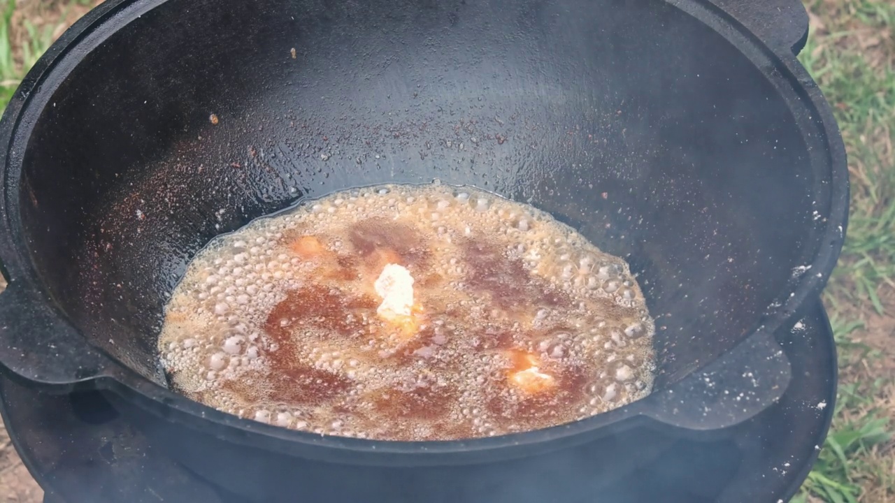 厨师正在木头上的大锅里煎鸡翅，油正在沸腾视频素材