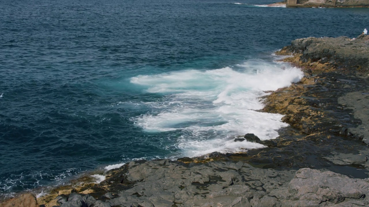 大西洋的海浪冲刷着特内里费海滩上潮湿的石头，阳光照耀着泡沫的水，天然的水池。视频素材