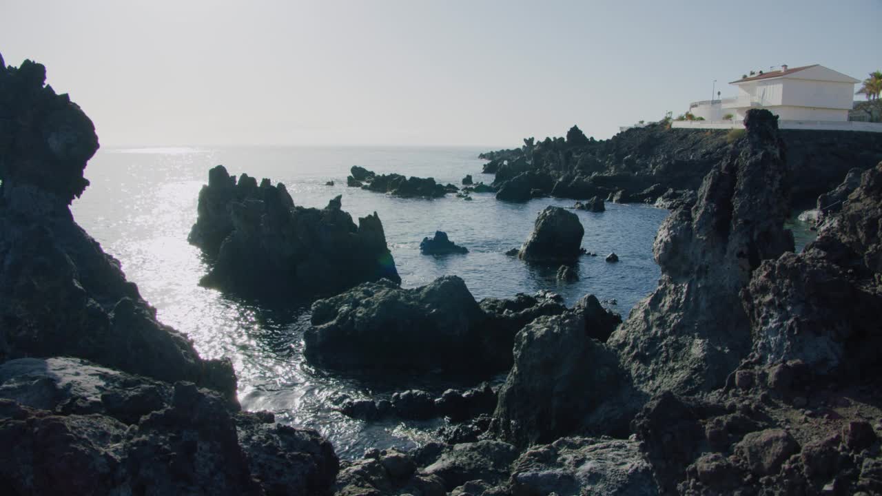 阳光明媚的海滩，黑色的火山熔岩石。视频素材