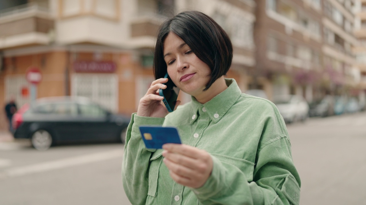 年轻的中国女人在街上拿着信用卡用智能手机聊天视频素材