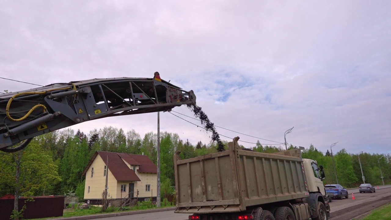 用升降机将旧沥青装进自卸车。道路工程视频素材