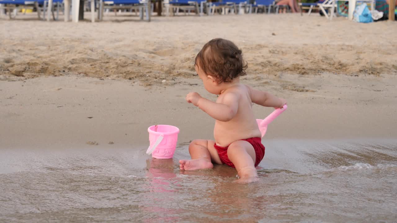 幼童蹒跚学步的女孩在希腊爱琴海浅水线沙滩上玩耍视频素材