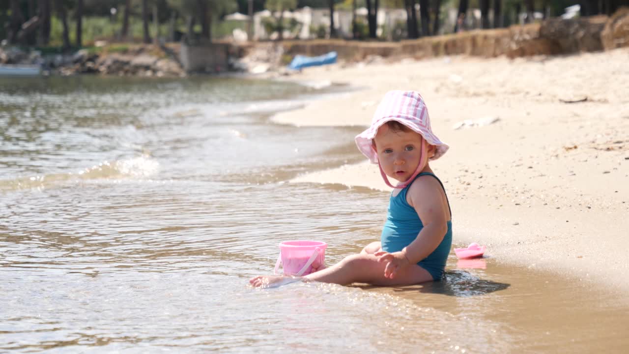 幼童蹒跚学步的女孩在希腊爱琴海浅水线沙滩上玩耍视频素材