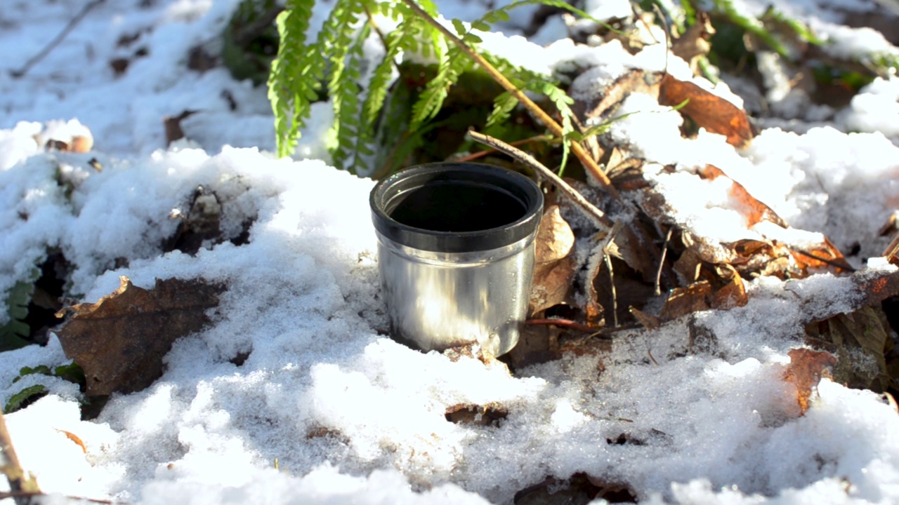 冬季森林里的登山杯，特写。男子将热茶从保温杯倒入钢杯。在寒冷的天气里喝热饮的概念视频素材