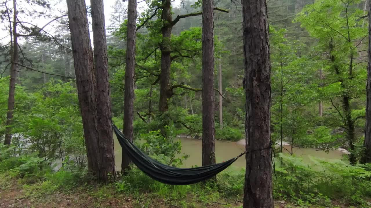 松林里一个雾蒙蒙的早晨，河边露营地的空吊床。放松和度假的概念。视频素材