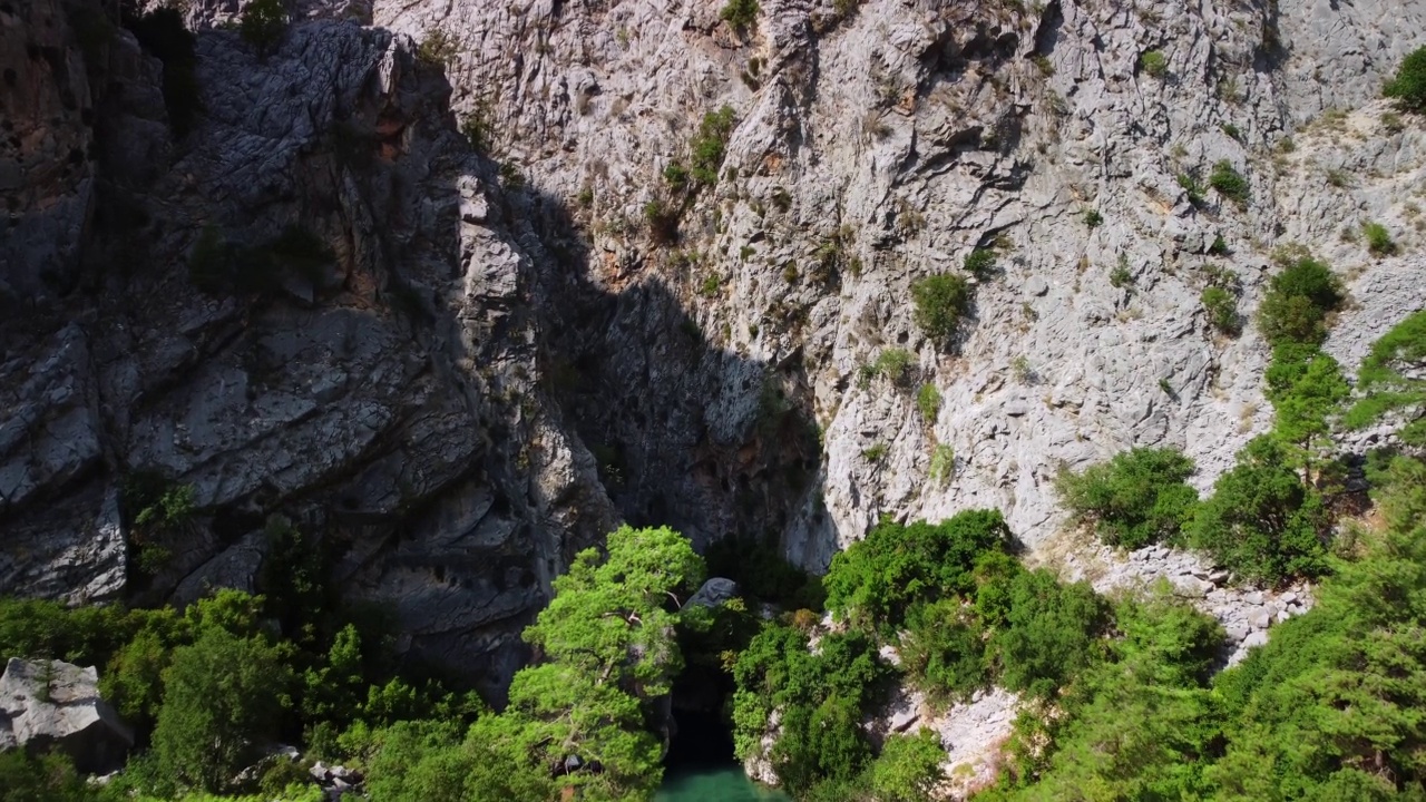 两个峭壁之间狭窄的岩石峡谷的鸟瞰图，上面覆盖着绿色的植被和树木视频素材