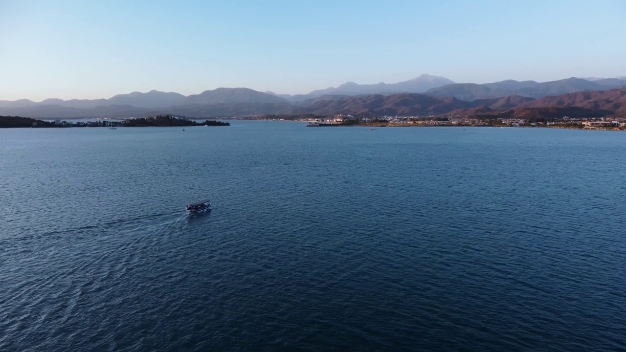 在晴朗的夏日，航拍摩托艇在海上游到地平线上的山脊视频素材