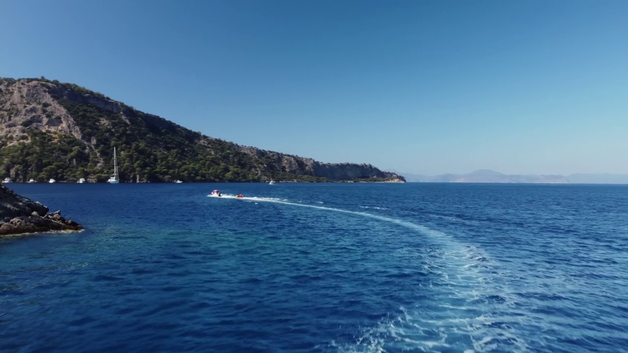 由无人机拍摄的岩石海岸线和摩托艇在波浪上行驶的海洋景观视频素材