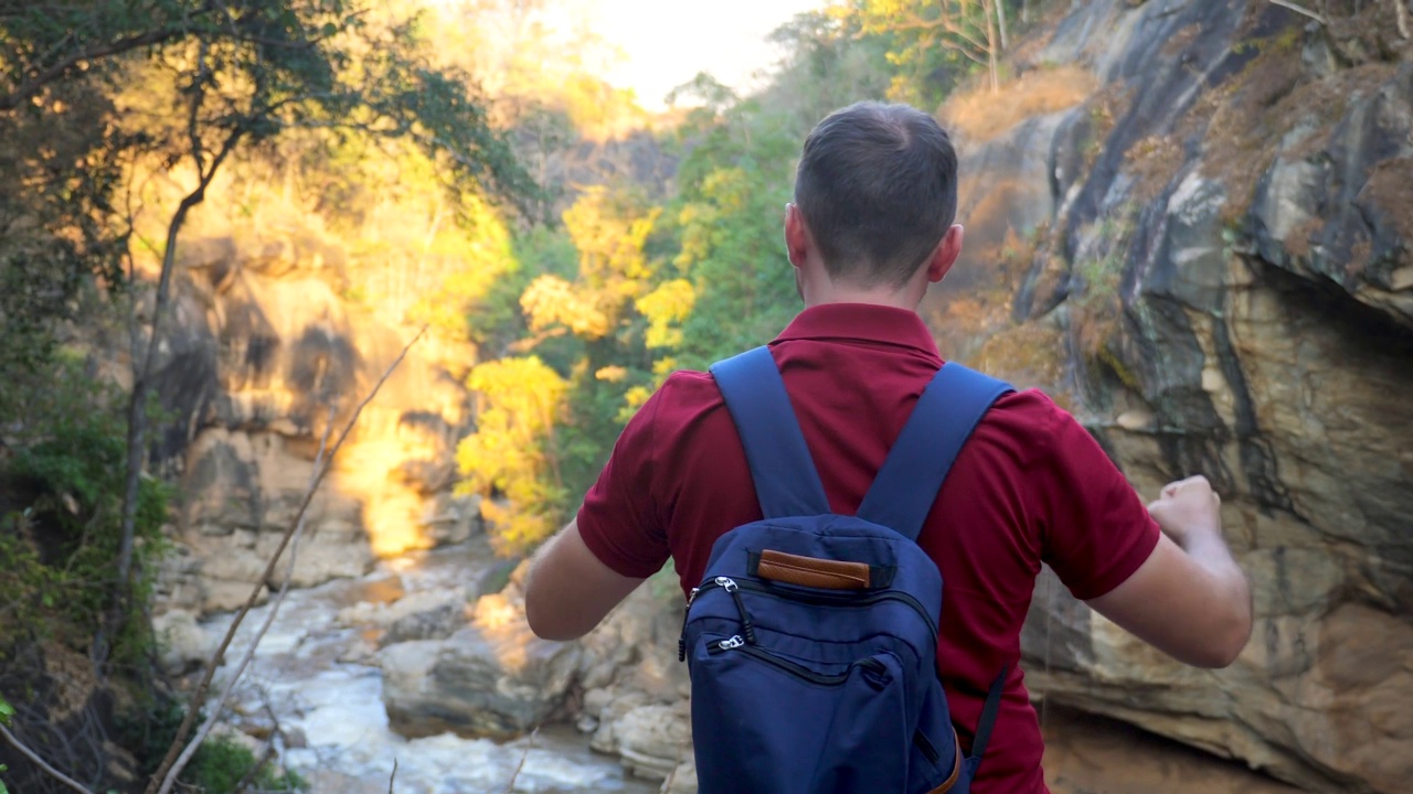 背着背包庆祝到达山顶的快乐旅行者。人类在山里旅行。徒步者胜利地举起手臂，庆祝成功，高兴地举起双手。旅游理念，积极的生活方式视频素材