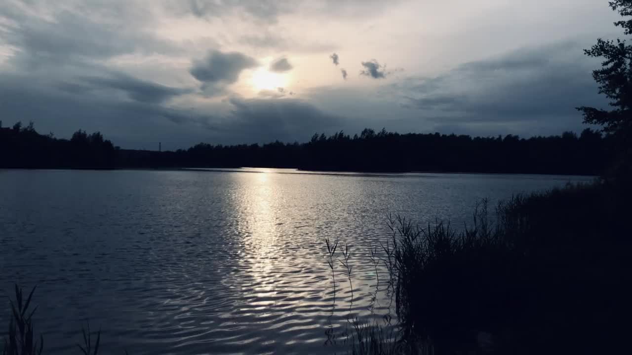 碧蓝的夏夜，多云的天空下，湖面泛起涟漪视频素材