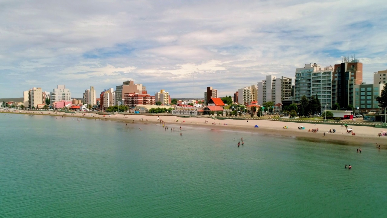 空中拍摄的游客在住宅城市的海滩，无人机在海上飞行向前-马德林港，阿根廷视频素材