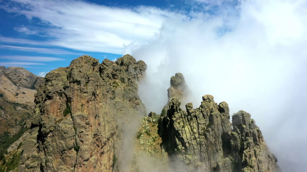 空中平移拍摄的戏剧性的云移动附近的岩层在晴天- Aiguilles de Bavella，法国视频素材