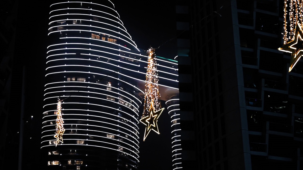 星形照明挂在电线上的现代建筑在夜晚照明城市-迪拜，阿拉伯联合酋长国视频素材