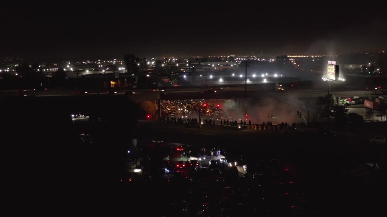 空中向前拍摄的人在桥上看街头赛车在晚上的城市-洛杉矶，加利福尼亚州视频素材