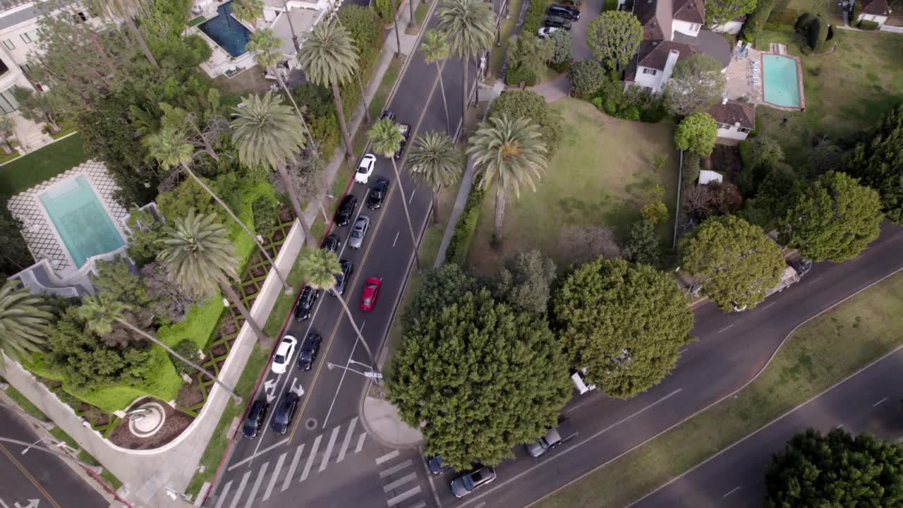 空中前进镜头的汽车移动在道路上的房子在城市-比弗利山，加利福尼亚州视频素材