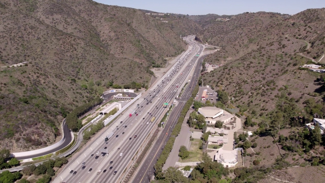 航拍汽车移动在道路上的山丘，无人机飞行在城市的阳光日-比弗利山，加利福尼亚州视频素材