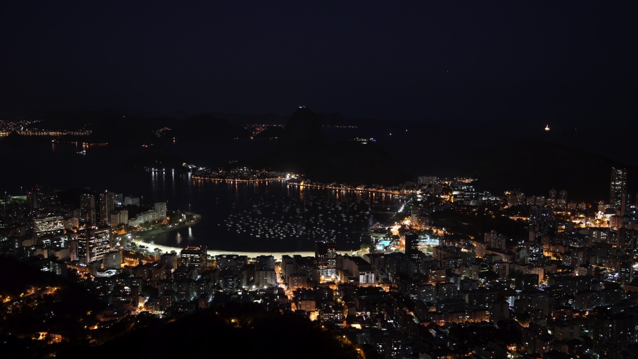 空中封锁拍摄的海上照明城市与甜面包山在晚上-里约热内卢，巴西视频素材