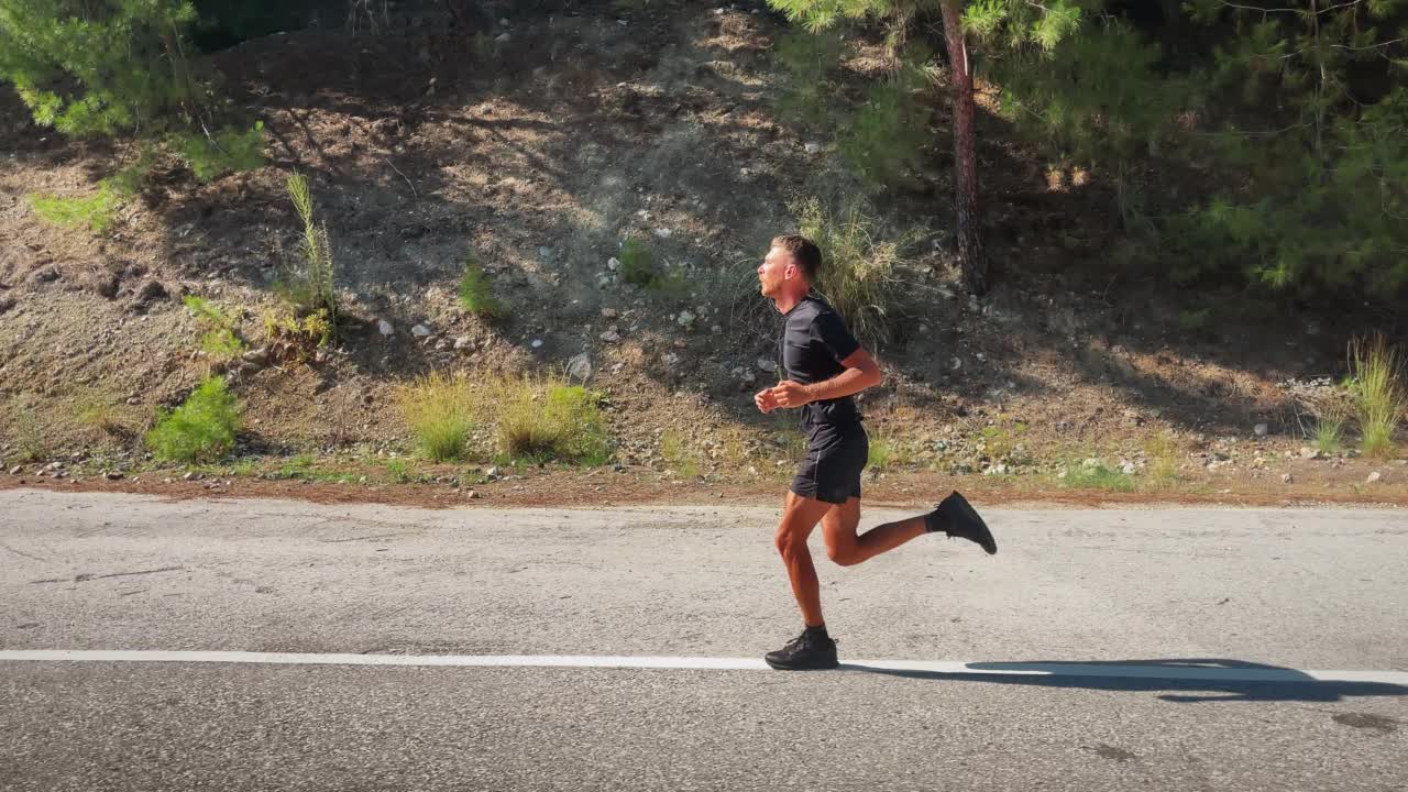 跑步运动训练。男子在户外慢跑，准备跑马拉松。运动员在做铁人三项运动。男人们在绿色的山路上奔跑。娱乐跑步锻炼。耐力跑步锻炼视频素材