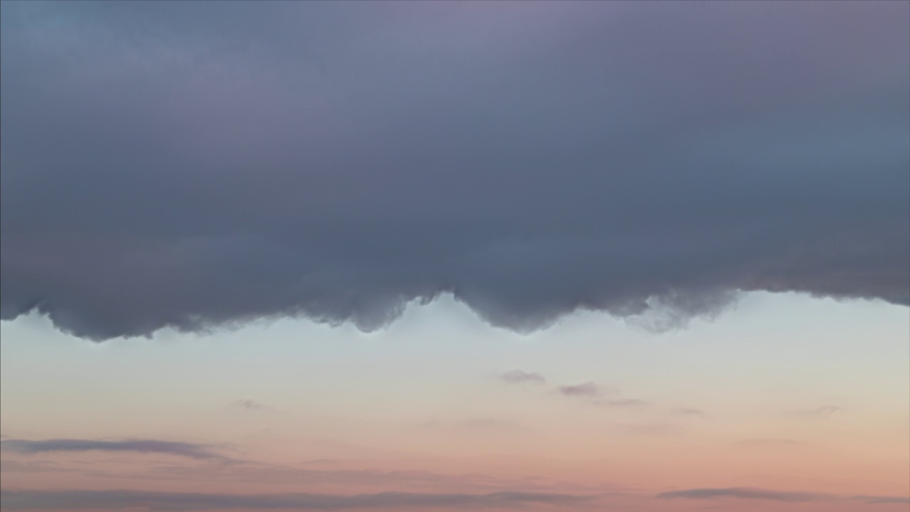 时间流逝。巨大的灰色阴雨乌云移动在冬天的夕阳橙色的天空视频素材