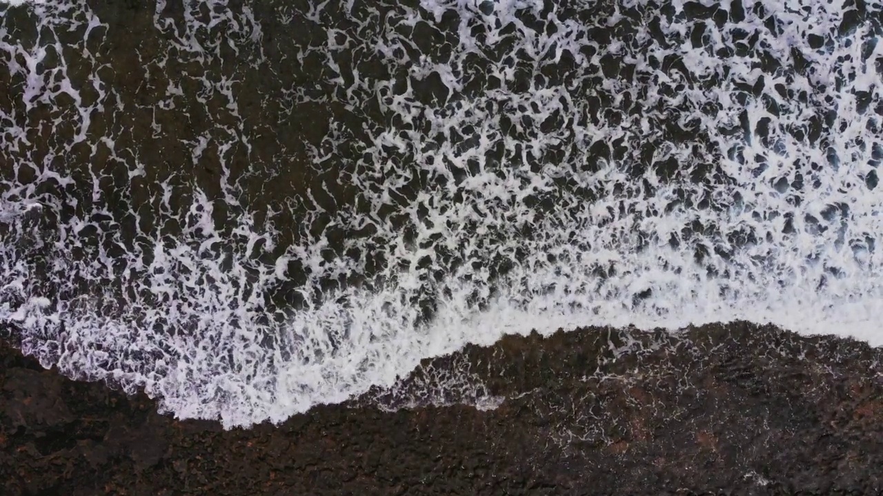 地球。海浪冲击着火山海滩。鸟瞰图视频素材