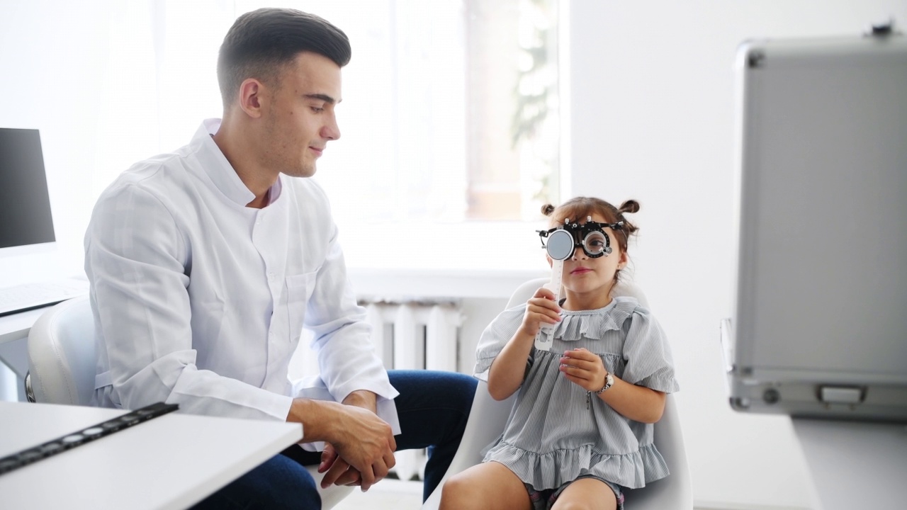 年轻的眼科医生戴着特殊的眼镜给小女孩检查视力视频素材