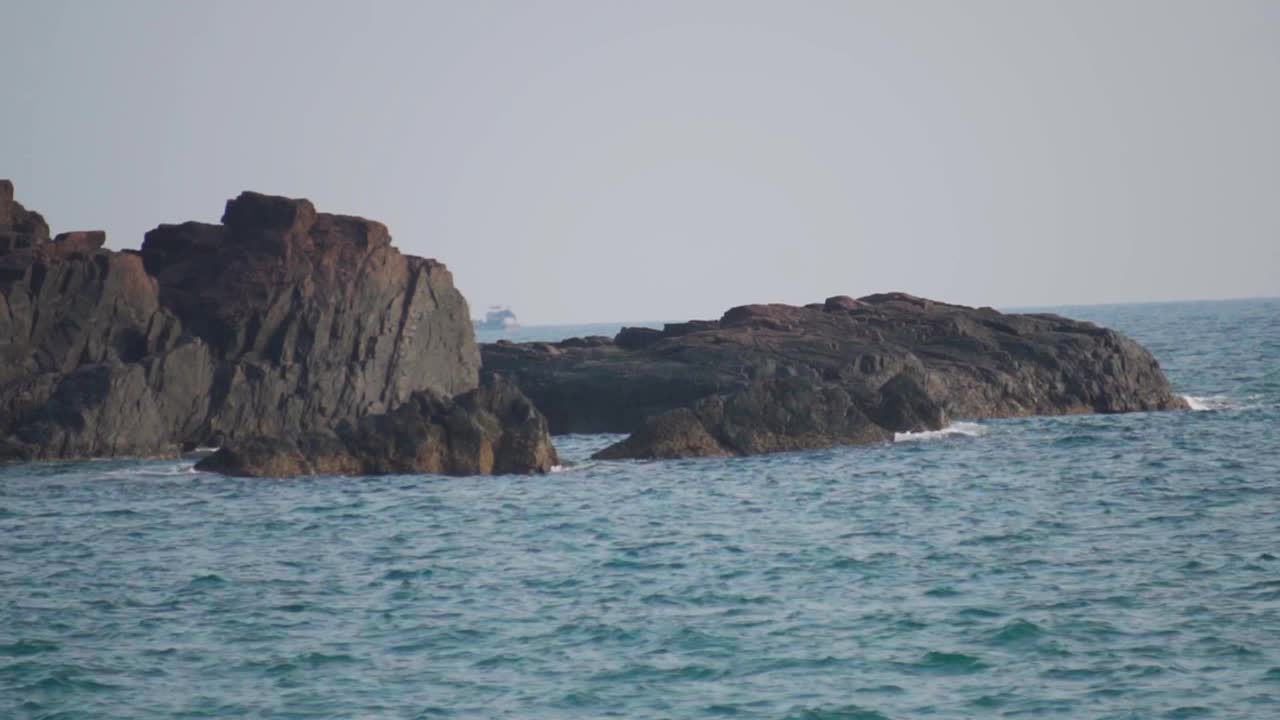 手持拍摄海浪撞击在海上的岩石，从Kakolem海滩在果阿，印度。海浪拍打着大海中央的岩石。在蓝色的海水中间的岩石。视频素材