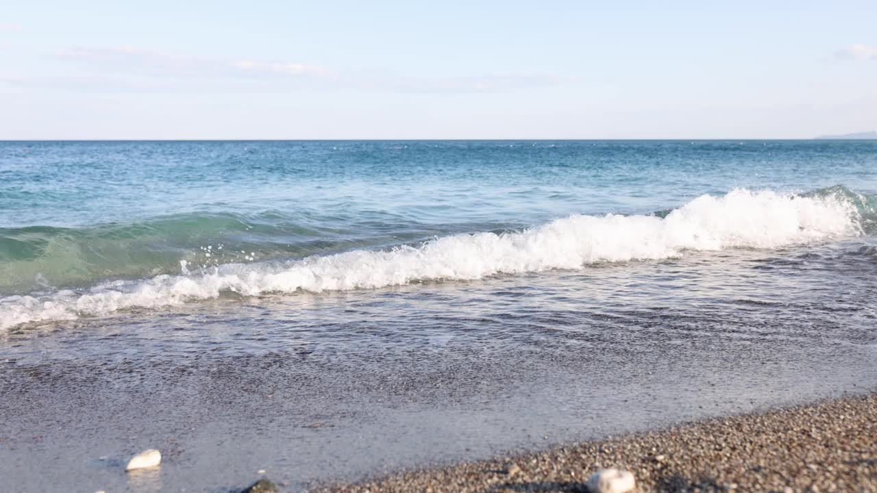 美丽的海边蓝色海浪，空旷的卵石滩视频素材