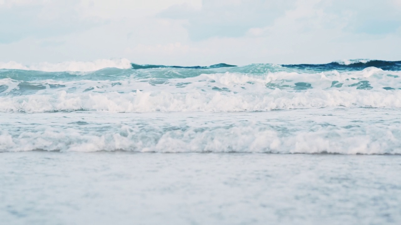 夏天的海滩、海沙和天空。海滩遇到深蓝色的海水和泡沫的波浪视频素材