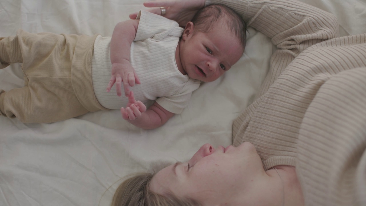 母亲和幼儿躺在床上互动的高角度视角视频素材