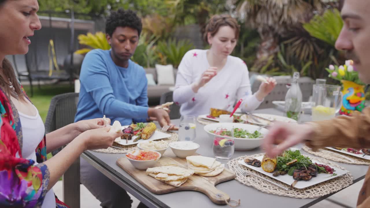 朋友们在露天餐桌上享用皮塔面包和蘸酱视频素材