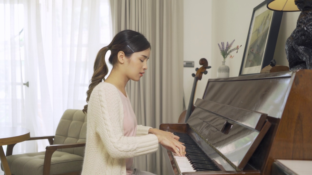 在聚会音乐表演中，在家中弹奏和练习钢琴歌曲的亚洲女音乐家。娱乐。庆祝活动。人们的生活方式。钢琴家的爱好视频素材