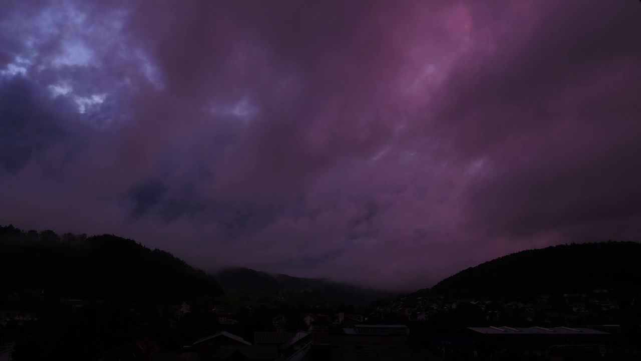 从白天到夜晚，粉红色的云在巨大的山峰上移动视频素材