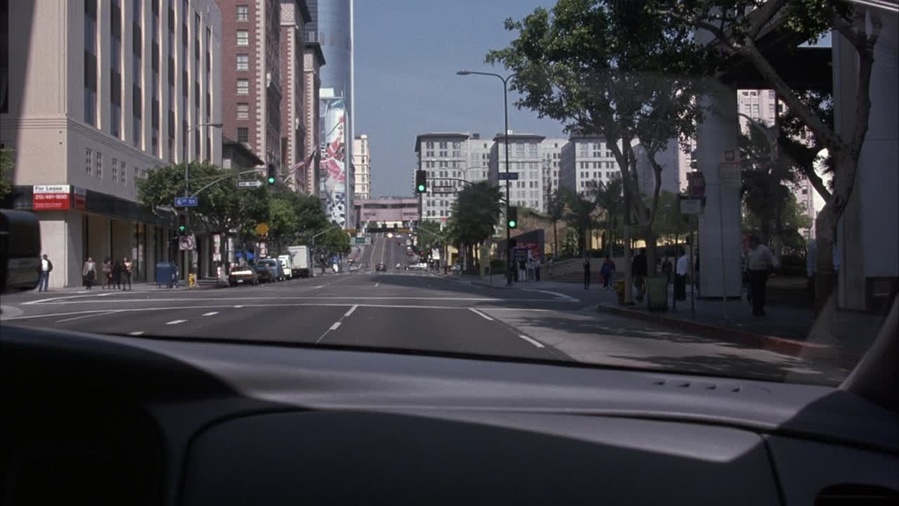 警车内部的中等角度。开着pov穿过洛杉矶市中心。接近交通路口。看见交通信号灯变红了。警车停了下来。两边车道上的汽车都开黄灯。参见“第六届圣”标志视频素材