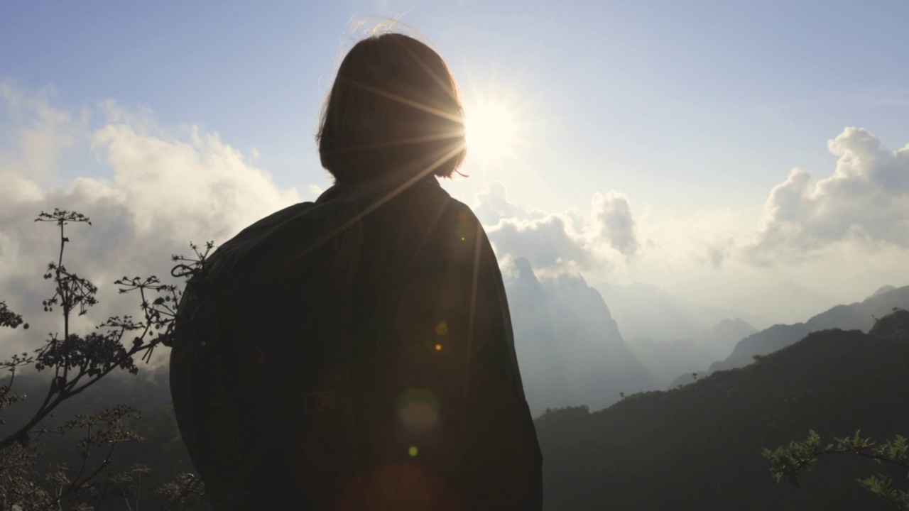 女人的剪影停留在山顶，享受全景。视频下载