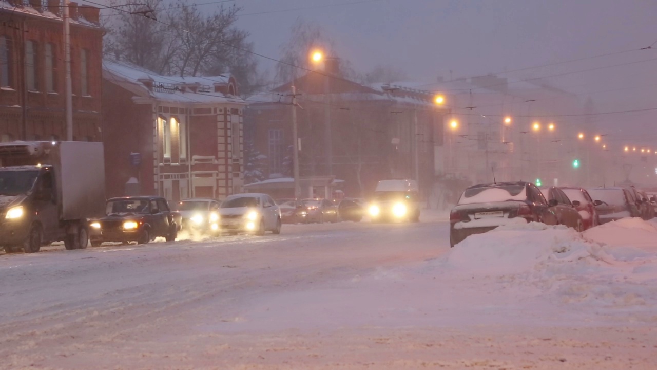 黎明时分，暴风雪中城市街道上的汽车视频素材