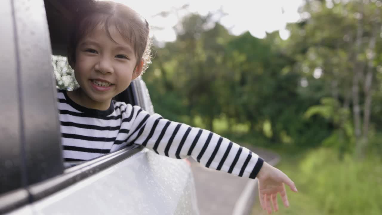 微笑的亚洲小女孩开车去夏天旅行旅行。视频下载