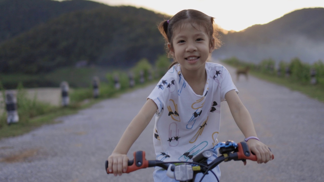 快乐的亚洲小女孩在户外骑自行车。视频下载