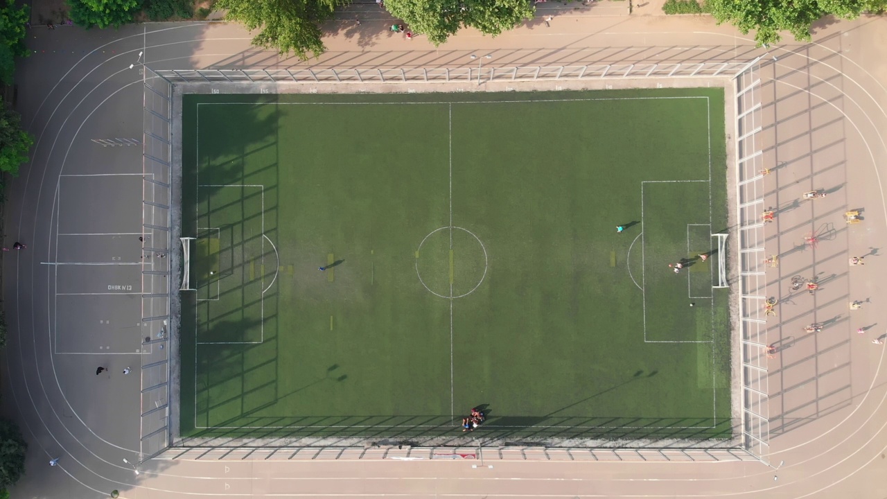 当地的孩子们在学校体育场的操场上踢足球。鸟瞰图视频素材