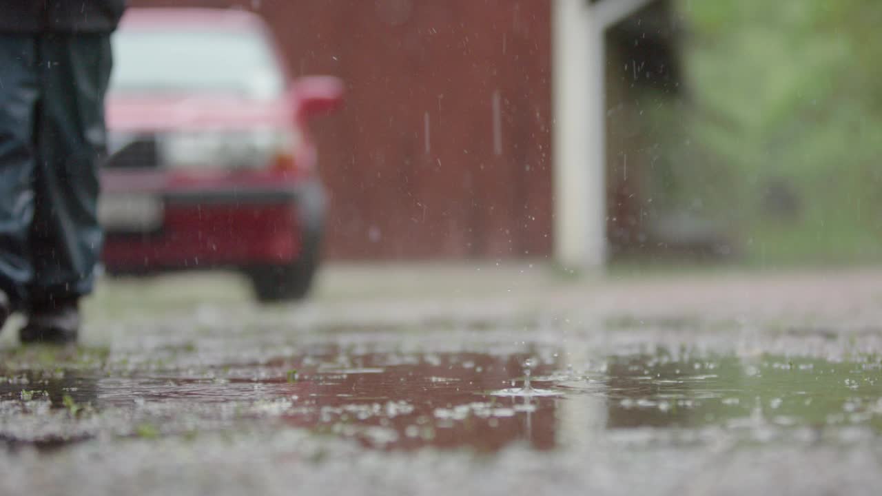 慢镜头，一个穿着雨衣的孩子在大雨中行走视频素材