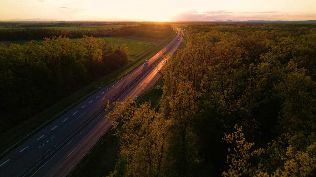 空中车辆移动在发光的高速公路周围的树木在夕阳的光视频素材