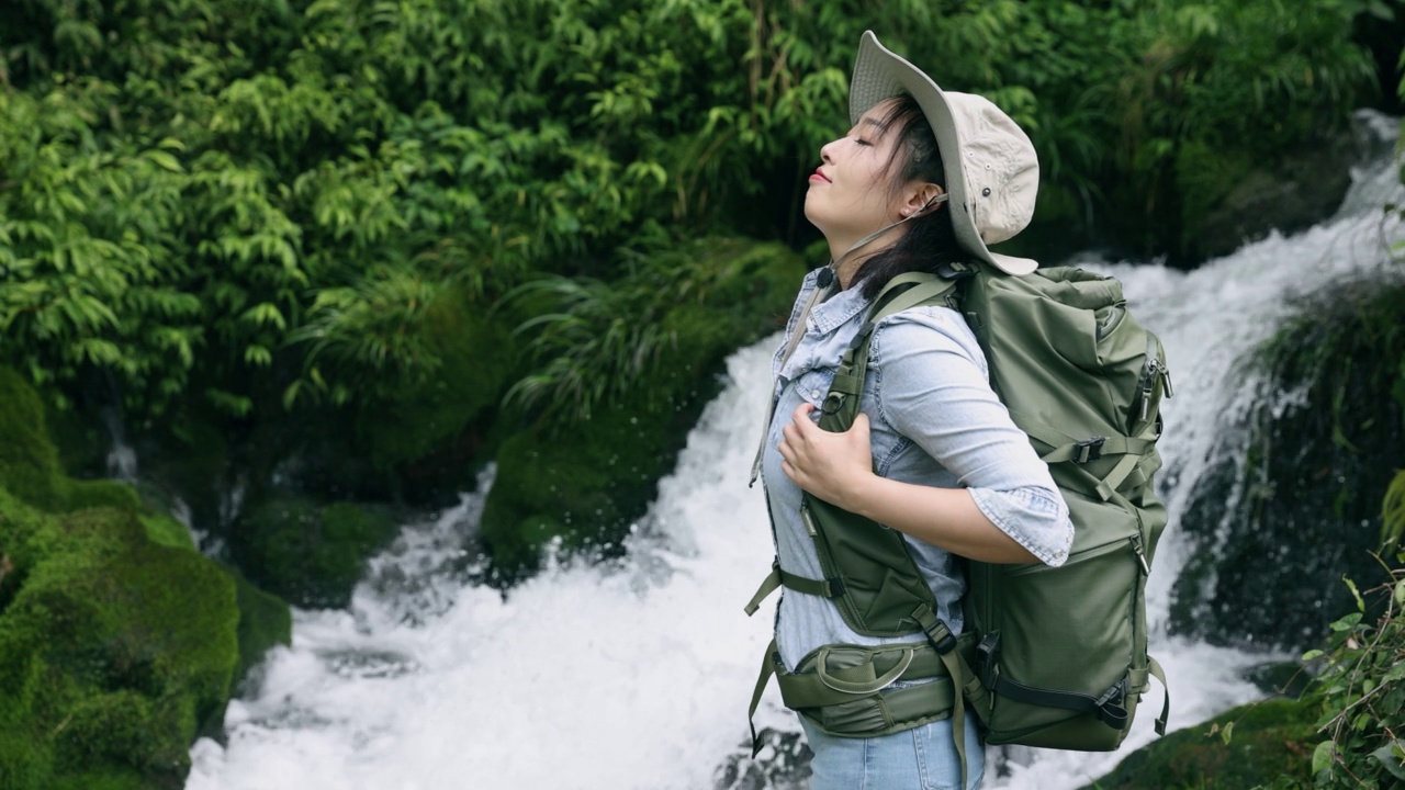 女徒步旅行者在山上的小瀑布中放松视频素材