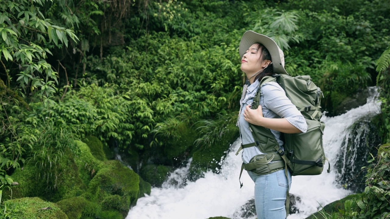 女徒步旅行者在山上的小瀑布中放松视频素材