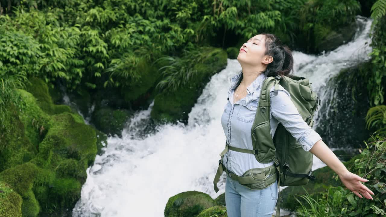 女徒步旅行者在山上的小瀑布中放松视频素材