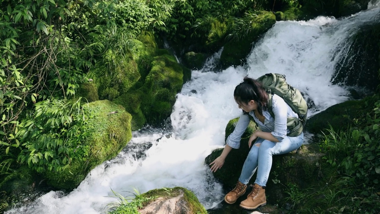 女徒步旅行者坐在瀑布旁休息视频素材