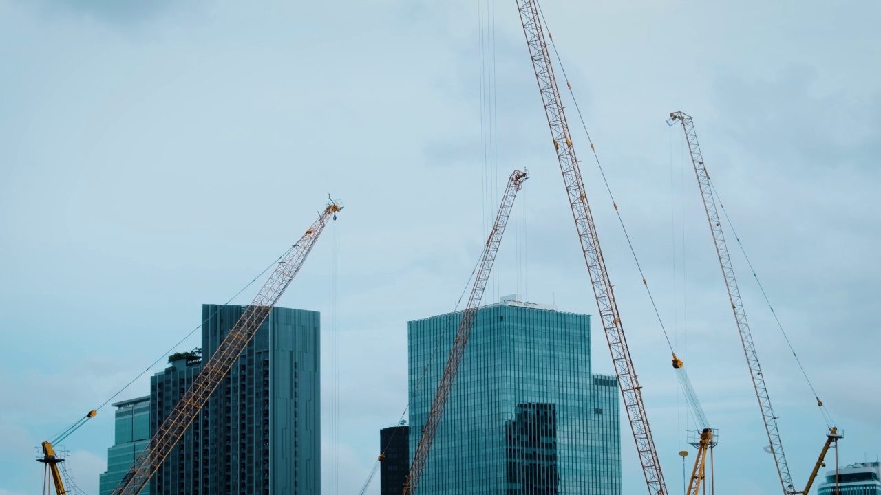 雨天施工起重机的剪影和未完工的住宅建筑在城市上空的日出。房屋建设，公寓楼视频素材