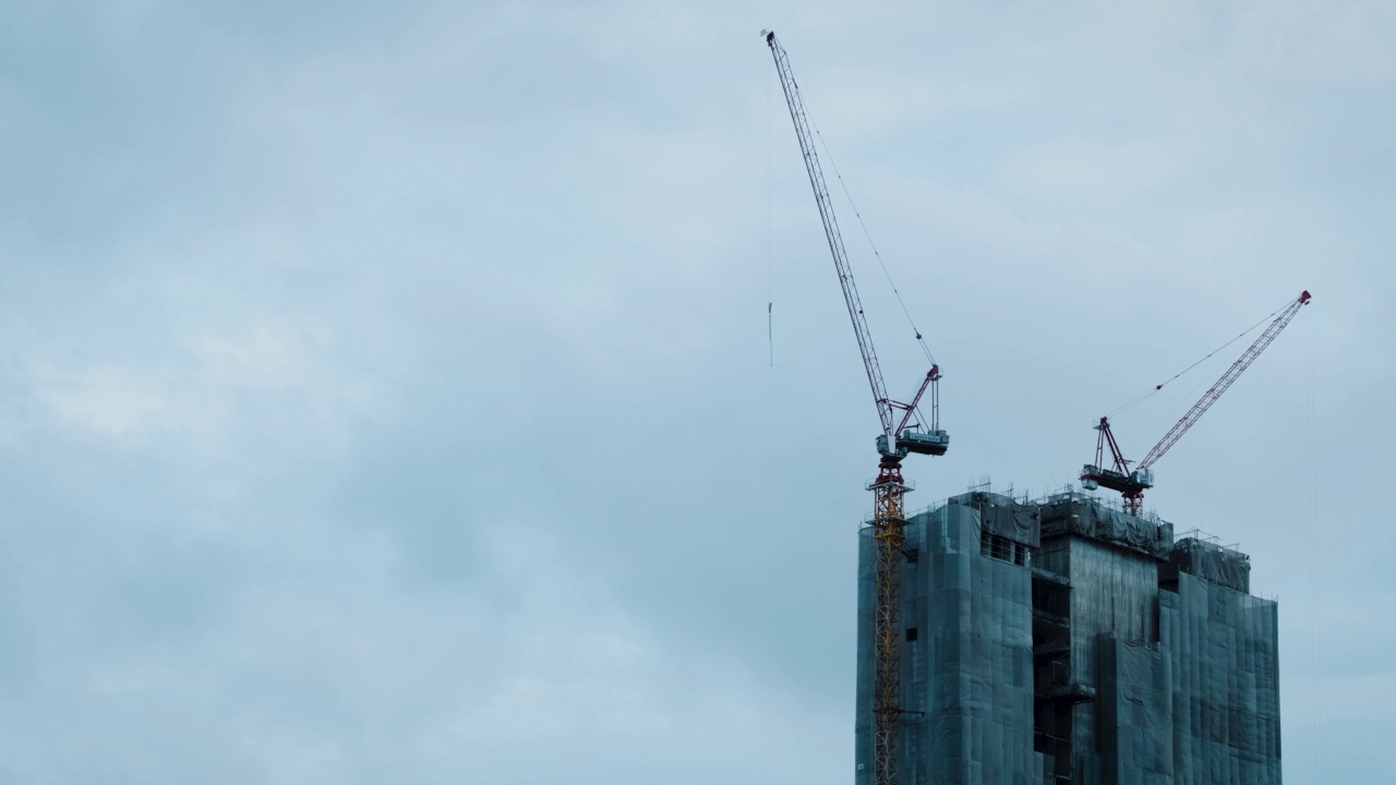 雨天施工起重机的剪影和未完工的住宅建筑在城市上空的日出。房屋建设，公寓楼视频素材