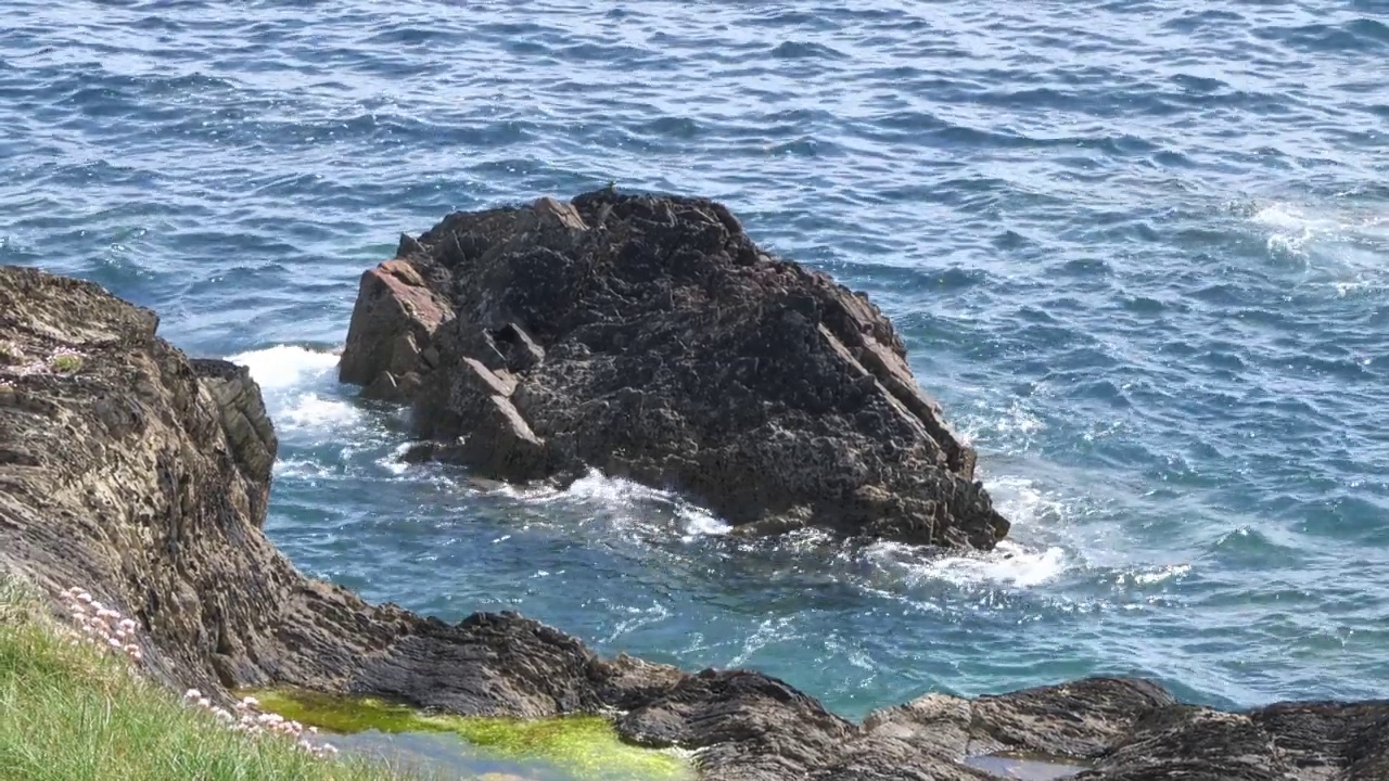 一块石头和绿松石海水，4k视频。海景，阳光明媚，天气温暖。手持视频。视频素材